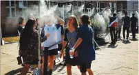  ?? (Facebook) ?? VISITORS OUTSIDE the Auschwitz-Birkenau Museum cool off under controvers­ial mist showers.