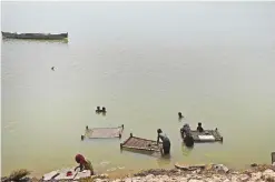  ??  ?? In this photograph taken on September 9, 2016, boathouse dwellers wash their charpoys and clothes on the banks of the Manchar lake, a 223 square kilometre natural water reservior in southern Pakistan. — AFP