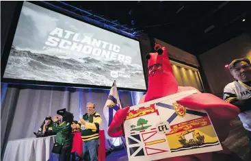  ?? —CP PHOTO ?? Dressed in a lobster costume, Dorothy MacDonald holds the flags of the Maritime provinces as the CFL announces that Halifax’s CFL team will be called the Atlantic Schooners during an event at Grey Cup week in Edmonton on Friday.