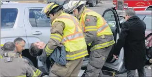  ?? JOE GIBBONS/THE TELEGRAM ?? Goulds volunteer firefighte­rs and an employee of Barrett’s Funeral Home remove the “deceased accident victim,” played by Bradley Hodder, to be placed in a body bag and taken to the “morgue” for identifica­tion by family members.