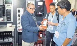  ?? PHOTO BY DAMION MITCHELL ?? Jamaican solar dealers Troy Moo Young (centre) and Damian Lyn (right) learn the specificat­ions of a solar battery from Antonio Galvez, director of sales for Latin America, at Energy Systems Americas.