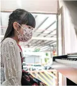  ??  ?? Piano student Yoyo, 6, wears a face mask during a piano lesson in a ‘piano truck’ in Hong Kong.