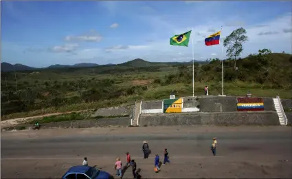  ?? AP Photo/ErAldo PErEs ?? In this March 10 file photo, people stand at the border between Venezuela (right) and Brazil, near the Brazilian city of Pacaraima, in Roraima state.