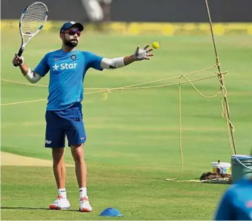  ?? — AFP ?? A different kind of training: India’s captain Virat Kohli using a tennis racquet and ball in training ahead of the Test against Bangladesh in Hyderabad today.