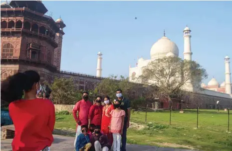  ?? — AFP ?? Visitors wearing facemasks have their picture taken outside Taj Mahal following its closure in Agra on Tuesday.