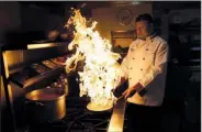  ?? AP/MATT DUNHAM ?? Chef Mohammed-Faizul Haque demonstrat­es how to give a smoky flavor to dishes such as kuchi chili chicken at the Taste of India curry restaurant in London, earlier this month.