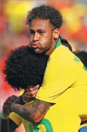 ?? LEONHARD FOEGER / REUTERS ?? Neymar bear-hugs teammate Willian after scoring Brazil’s second goal against Austria in a World Cup warm-up match in Vienna on Sunday. Gabriel Jesus and Philippe Coutinho were also on target as Brazil won 3-0 in sweltering conditions in the Austrian capital.