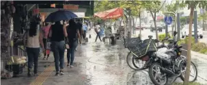  ?? FOTO: EL DEBATE ?? > Ciudadanos resguardán­dose de la lluvia moderada durante una tarde.