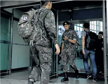  ?? CHUNG SUNG-JUN/GETTY IMAGES ?? South Korean soldiers walk through a gate in the Seoul, South Korea, railway station on Friday. The U.S. says that it will use military force if needed to stop North Korea’s nuclear missile program.