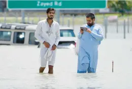  ?? JON GAMBRELL/AP ?? Men wade through floodwater­s Wednesday in Dubai, United Arab Emirates. A storm dumped over 5.59 inches of rain late Monday and Tuesday in Dubai over 24 hours.