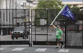  ?? ASSOCIATED PRESS ?? Mike Pellerin waves a Donald Trump campaign flag near a barricade in downtown Tulsa on Friday ahead of President Donald Trump’s campaign rally tonight.