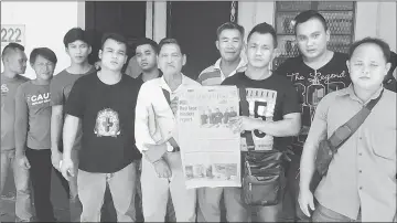  ??  ?? The group of Penans, with one of them holding up the Dec 22, 2016, issue of The Borneo Post, in a photo-call outside the police station. Clement is fourth from right (wearing stripped T-shirt).