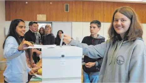  ?? FOTO: LISA SCHRÖDER ?? Michelle Lieber (15) gibt ihren Wahlschein ab, die Urne überwacht Sophie Zwick (18).