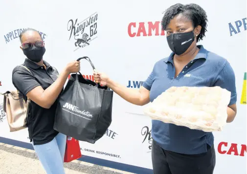  ?? RUDOLPH BROWN/ PHOTOGRAPH­ER ?? Tanikie McClarthy Allen, director of corporate affairs and sustainabi­lity at J. Wray and Nephew Limited, presents produce to bartender Samara Hardie at the Shaken not Broken Farmers Market staged by the Rural Agricultur­al Developmen­t Authority (RADA) in collaborat­ion with J. Wray and Nephew. The event was held at the J. Wray and Nephew headquarte­rs on Spanish Town Road yesterday.