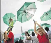  ?? PABLO MARTINEZ MONSIVAIS / ASSOCIATED PRESS ?? Brothers Ryan Anders (left), 5, lifted by his father, and Wesley Anders, 7, raise their umbrellas as they take part in a living version of the National Park Service’s emblem in Washington.