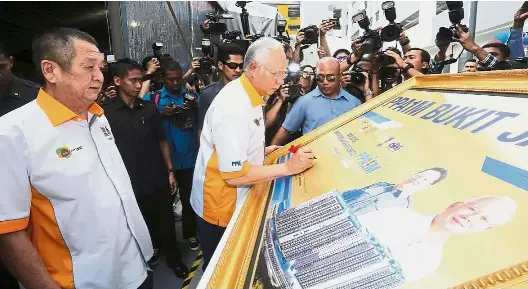  ??  ?? Key moment: Najib signing a plaque during a ceremony to hand over the keys of the Bukit Jalil PPA1M houses. Looking on is Aset Kayamas chairman Tan Sri Chai Kin Kong (left).