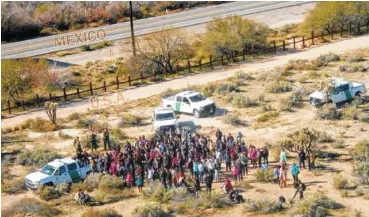  ?? PHOTO BY U.S. CUSTOMS AND BORDER PROTECTION VIA AP ?? Migrants, apprehende­d after illegally crossing along the U.S.-Mexico border near Lukeville, Ariz., gather together. A group of 325 Central Americans surrendere­d to agents Thursday after entering the United States illegally. Mexico is at the top of the image, beyond the border fence.