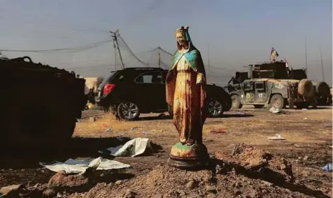  ??  ?? A statue of Virgin Mary is abandoned on a street in Bartella on Sunday. Iraqi forces captured Bartella, around 15km east of Mosul.