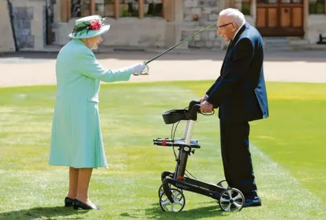  ?? Foto: Chris Jackson, dpa ?? Der Moment, über den Tom Moore sagte: „Ich hätte mir niemals vorstellen können, dass mir das passieren würde.“Am 17. Juli 2020 schlug Queen Elizabeth II. den Senior zum Ritter. Mit seinem Rollator lief er über hundert Runden durch seinen Garten und sammelte Millionen Pfund für das britische Gesundheit­ssystem.