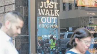  ?? COLIN BOYLE/SUN-TIMES FILE ?? People use their phones outside of the Amazon Go Chicago location at 113 S. Franklin Street on its opening day in September.