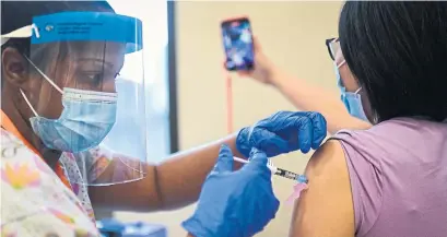  ?? NATHAN DENETTE THE CANADIAN PRESS FILE PHOTO ?? Long-term-care nurse Limin Liu takes a selfie as nurse Sasha Vartley vaccinates her with the Pfizer vaccine in Toronto on Dec. 15.