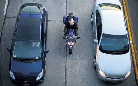  ?? Noah Berger / Special to The Chronicle 2013 ?? A motorcycli­st
weaves between lanes of stalled traffic, a practice known as lane-splitting,
during the commute on Highway 24 in
Oakland. Although it remains legal, the California Highway
Patrol recently removed lane-splitting
safety guidelines...