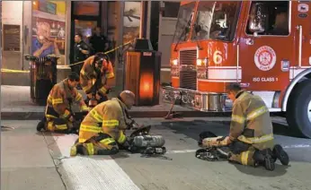  ??  ?? Pittsburgh firefighte­rs adjust their air tanks to get ready to go back into the Midtown Towers at 643 Liberty Ave., Downtown, where a seven-alarm fire killed a woman Monday.