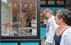  ?? ANGELA WEISS/ AFP/TNS ?? A couple walks past a “now hiring” sign posted at a store in New York City on Aug. 20, 2021. The number of available job openings rose to 10.9 million
during July.