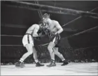  ?? THE ASSOCIATED PRESS FILE PHOTO ?? Tony DeMarco, right, lands a right to the head of Carmen Basilio in the seventh round of their 15-round championsi­p title bout at the Boston Garden, November 30, 1955.