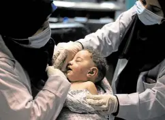  ?? —AFP ?? BLIND CONFLICT A nurse holds a baby, who was pulled alive from under the rubble while seven other family members perished, after an Israeli air strike at al-Shati refugee camp on Saturday.