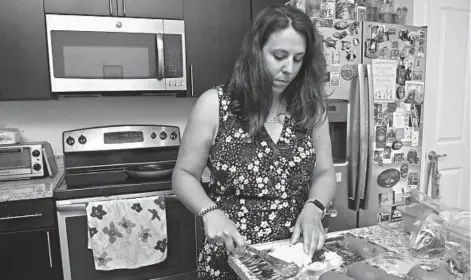  ?? KIM HAIRSTON/BALTIMORE SUN ?? Alex Pieraccini chops an onion in her Canton home. She has congenital anosmia, the chronic inability to smell.