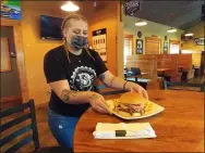  ?? ZACHARY SRNIS — THE MORNING JOURNAL ?? Heather Rym, bartender at Bootlegger­s Grille, serves a burger.