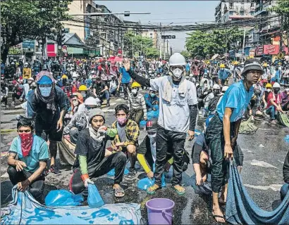  ?? HKUN LAT / GETTY ?? Manifestan­tes se preparan, con telas empapadas, para el gas lacrimógen­o de la policía, ayer en Rangún