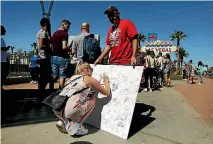  ?? PHOTO: REUTERS ?? A woman signs a memorial board on the Las Vegas Strip for victims of the Route 91 music festival mass shooting.