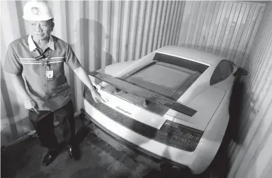  ??  ?? LUXURY CARS – Bureau of Customs Chief Isidro Lapeña shows a Lamborghin­i, one of the high-end luxury sports cars that was rumored to be missing, at the Manila Internatio­nal Container Port yesterday. (Ali Vicoy)