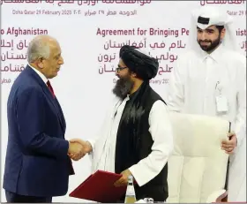  ?? HUSSEIN SAYED — THE ASSOCIATED PRESS ?? U.S. peace envoy Zalmay Khalilzad, left, and Mullah Abdul Ghani Baradar, the Taliban group’s top political leader, shake hands after signing a peace agreement between Taliban and U.S. officials in Doha, Qatar, on Saturday.