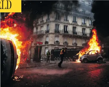  ?? ABDULMONAM EASSA / AFP / GETTY IMAGES ?? Protesters walk past burning cars in Paris during weekend clashes with riot police. Activists in yellow jackets torched cars, smashed windows, looted stores and tagged the Arc de Triomphe with multicolor­ed graffiti.
