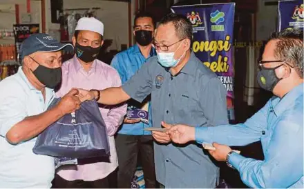  ?? (Foto BERNAMA) ?? Isa (kanan) mengiringi Timbalan Menteri Sumber Manusia, Datuk Awang Hashim menyampaik­an sumbangan kepada Wan Ahmad Wan Ismail pada Majlis Jualan Pra-syawal di Pasar Tani Kekal Guar Chempedak, semalam.