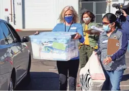  ?? DRAKE PRESTO/THE REPUBLIC ?? Kristen Nordquist, left, the manager of the Women Veteran’s Program, carries a bin of supplies to a mother’s car during a drive-thru baby shower at the Phoenix VA Health Care System on Saturday.