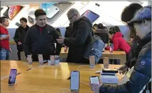  ?? ANDY WONG / AP ?? People check out the latest iPhone on Tuesday at an Apple Store in Beijing. China’s economy czar and the U.S. Treasury secretary have discussed plans for talks on the tariff battle.