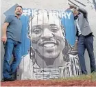  ?? KAYLA O’BRIEN/STAFF ?? Artist Jeff Sonksen, left, painted a mural for a welcome-back party Thursday for Henry Dorvil, who returned to Sanford after a year in Haiti.