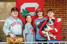  ?? JIM NOELKER/STAFF ?? The Koch family of Springboro — (from left) John, his wife Stacey, John and Jeff (and dog J.J.) — will be rooting for the Ohio State Buckeyes when the team plays against Michigan today in Columbus. Stacey is from Michigan, and her family will be cheering on the Michigan Wolverines.