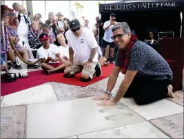  ?? ?? Surfers' Hall of Fame inductee Peter Mel puts his imprint in concrete during the ceremony on Main Street in Huntington Beach on Friday.