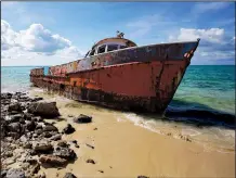  ??  ?? A corroding fishing boat, abandoned after its captain passed away, lists on a beach in Exuma Sound on Cat Island, Bahamas.