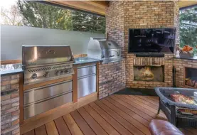  ??  ?? A classic wood burning fireplace and built-in barbeque with accessorie­s is encased in brick from the existing front façade.