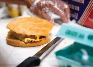  ?? (AP Photo/Seth Wenig, File) ?? Hector Perez prepares to wrap a bacon, egg and cheese sandwich at a bodega in the Bronx section of New York. While some travelers cringe at the thought of greasy sausages and bland eggs served at the free hotel breakfast buffet, others say free breakfast ranks among their favorite aspects of travel. Hilton says “free breakfast” is the most used search filter on its website. In 2023, some hotels are revamping their offerings to try to change the minds of even the most skeptical travelers, offering healthier, customizab­le choices that include DIY yogurt bowls and higher-protein dishes, plus more flexible eating hours.