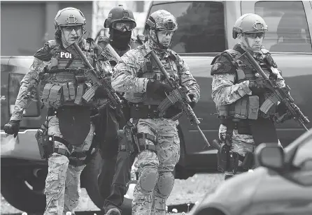  ??  ?? ANDREW VAUGHAN / THE CANADIAN PRESS FILES Emergency response officers check a Moncton residence in June 2014 searching for a suspect who shot and killed three RCMP officers.