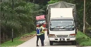  ??  ?? Stringent inspection: Police officers checking on a lorryata roadblock near the PenangKeda­h border.