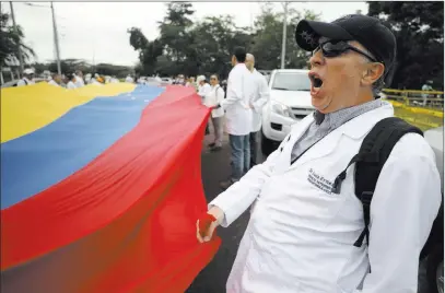  ?? Fernando Vergara The Associated Press ?? Venezuelan doctors shout slogans Sunday against the government of Nicolas Maduro at the Internatio­nal Bridge Tienditas. They demanded that their nation’s military allow humanitari­an aid into the country.