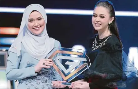  ?? PIC BY KHAIRUL AZHAR AHMAD ?? Last year’s ‘Clever Girl’ winner, Fatin Nuraisya Mohd Hanipha (left) presenting a trophy to the reality television show’s new champion, Sara Amelia Muhammad Bernard, at Plaza Alam Sentral in Shah Alam last Friday.